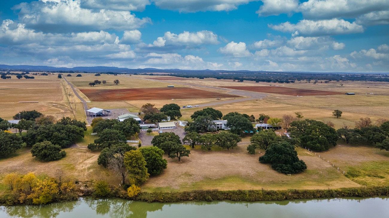 An aerial view of the Texas White House and airstrip under a bright blue sky.