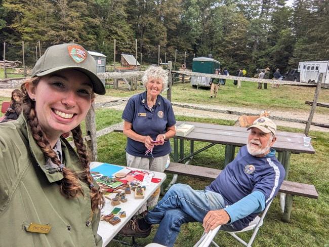 park ranger poses for selfie with two park volunteers in blue polo shirts