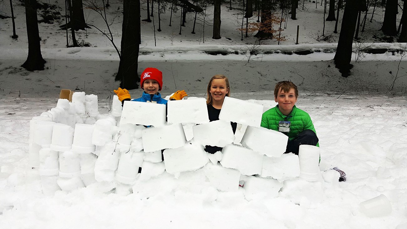 blocks of snow piled up with kids behind them