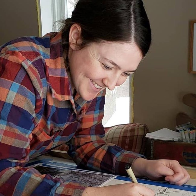 Woman leaning over a sketch book and smiling