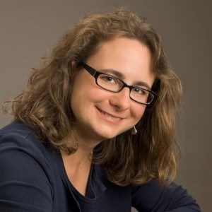 headshot of woman with glasses and blue shirt smiling at camera