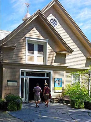 Two visitors walk toward the door of the Carriage Barn Visitor Center in summer