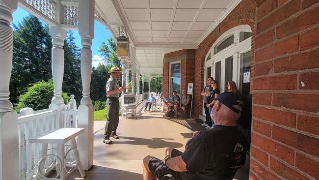 Ranger talks to visitors on mansion porch