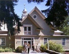 Visitors linger in the sun in front of the beige three-story renovated barn, whose steepled dormers point toward the blue sky. NPS Photo. Visitors linger in the sun in front of the beige three-story renovated barn, whose steepled dormers point toward the blue sky. NPS Photo.