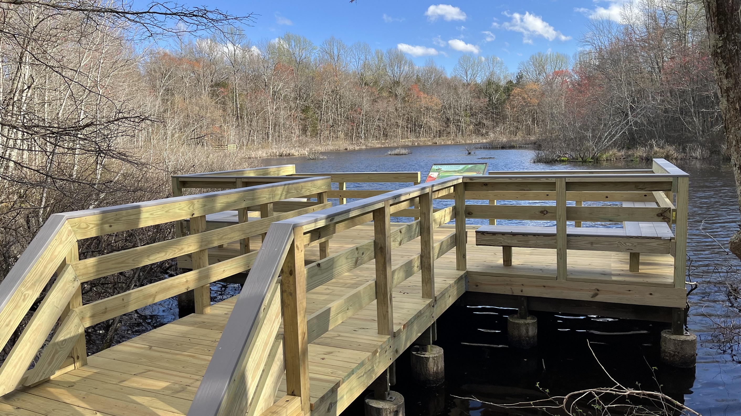 Sloan's Crossing Pond Overlook in Mammoth Cave National Park A large wooden deck sits above a dark body of water surrounded by woods.
