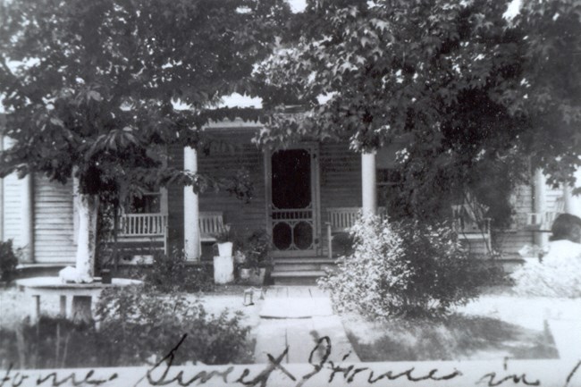 A black and white photo of the front of a small hotel.