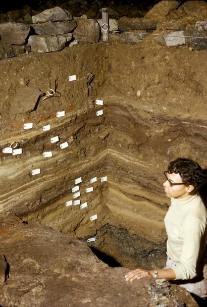 A women sitting in a large dug out pit.