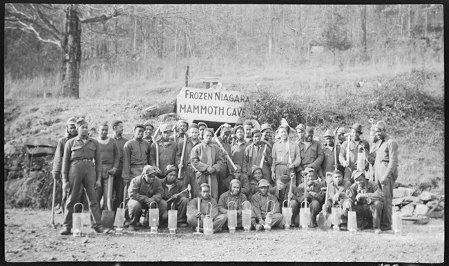 A black and white photo of a group of men standing outside the Frozen Niagara Entrance