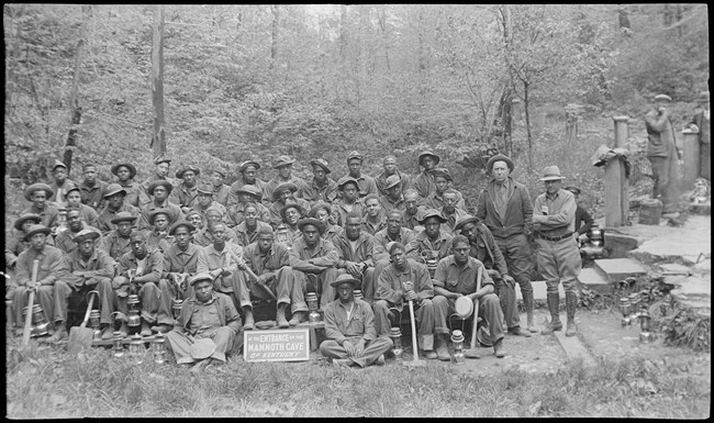 A group of men sit for a photo near the entrance to mammoth cave.
