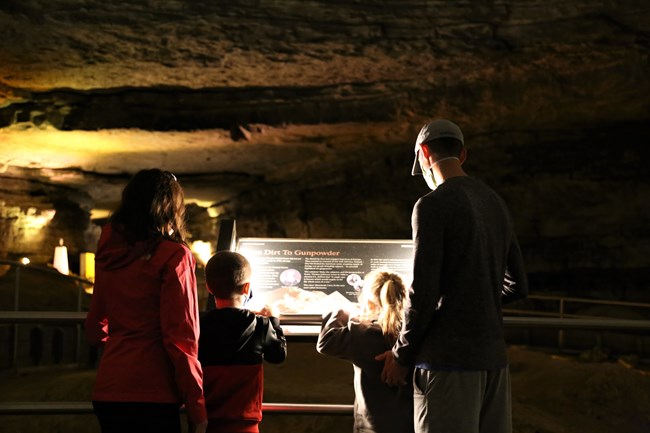 A family reading a wayside sign inside Mammoth Cave
