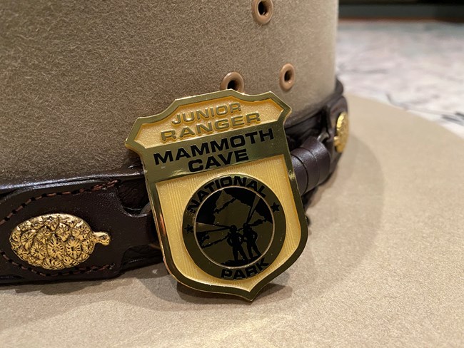 A plastic junior ranger badge leaning against a park ranger flat hat.