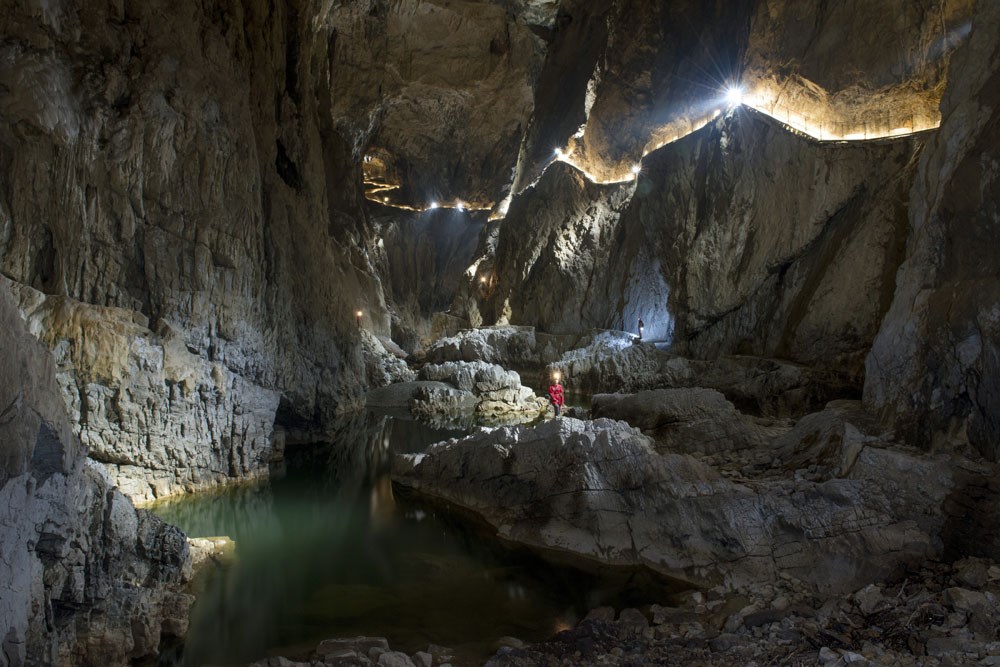 A large cave room with a person standing in the middle