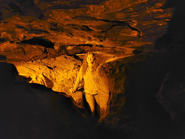 A small narrow cave passage with a woman standing in the passage.