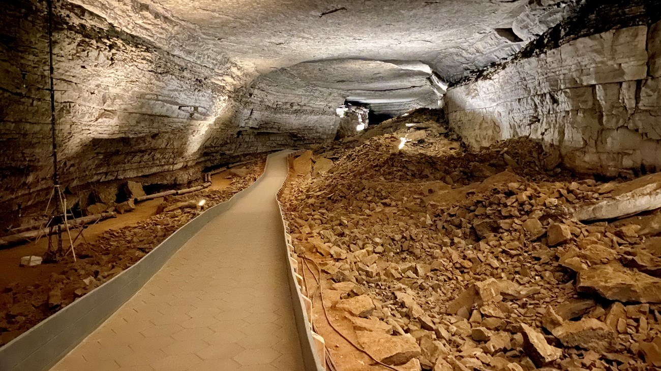 A paved trail travels through a large cave passage.