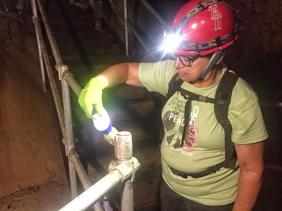 A NSS volunteer, Paula, scrubs clean a metal handrail in the cave