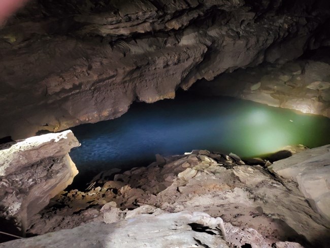 A pool of blue green water in a cave passage.