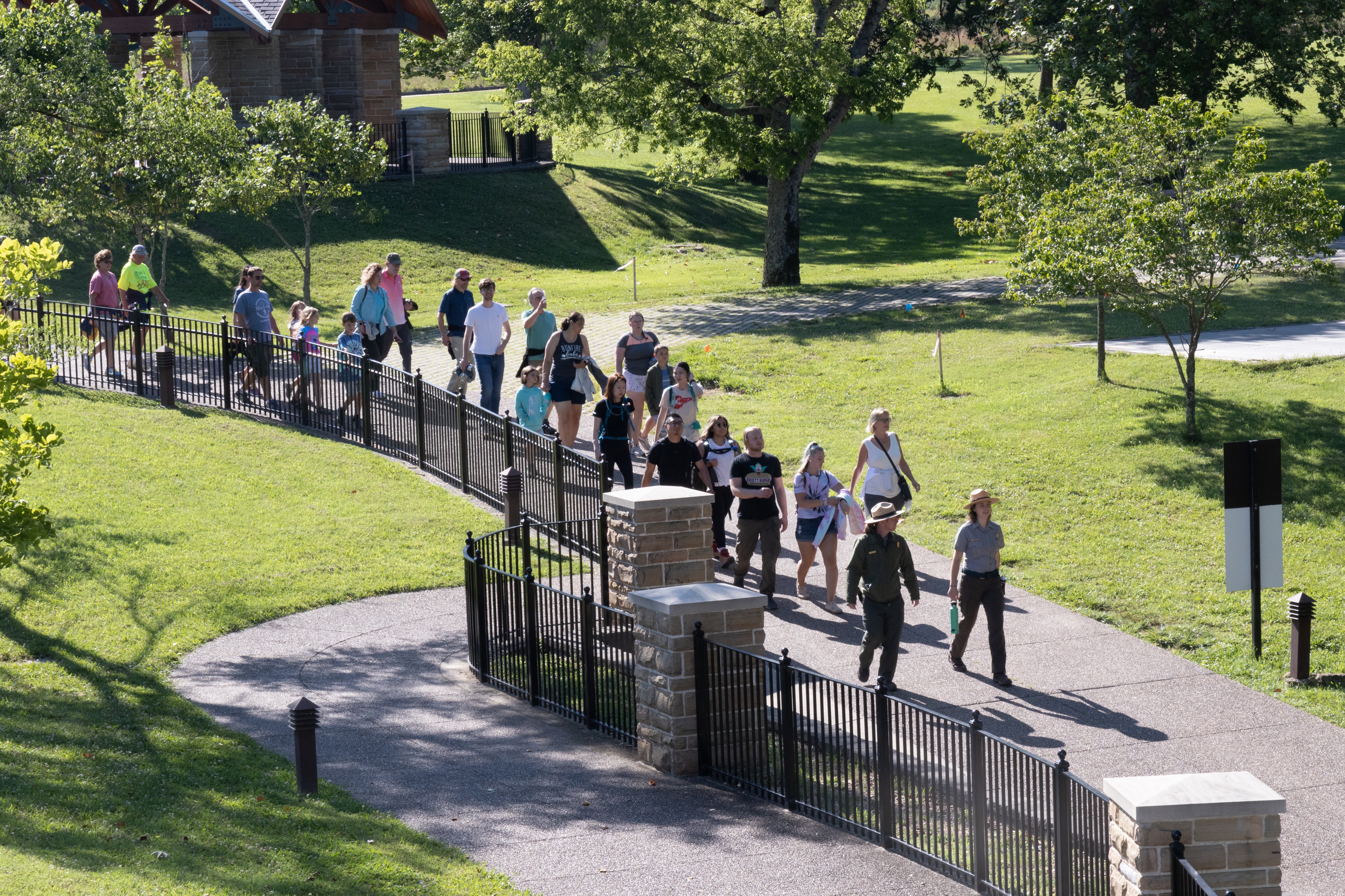 Mammoth Cave National Park welcomes hundreds of thousands of visitors to the park and cave tours annually. A large group of people walk along a paved pathway.