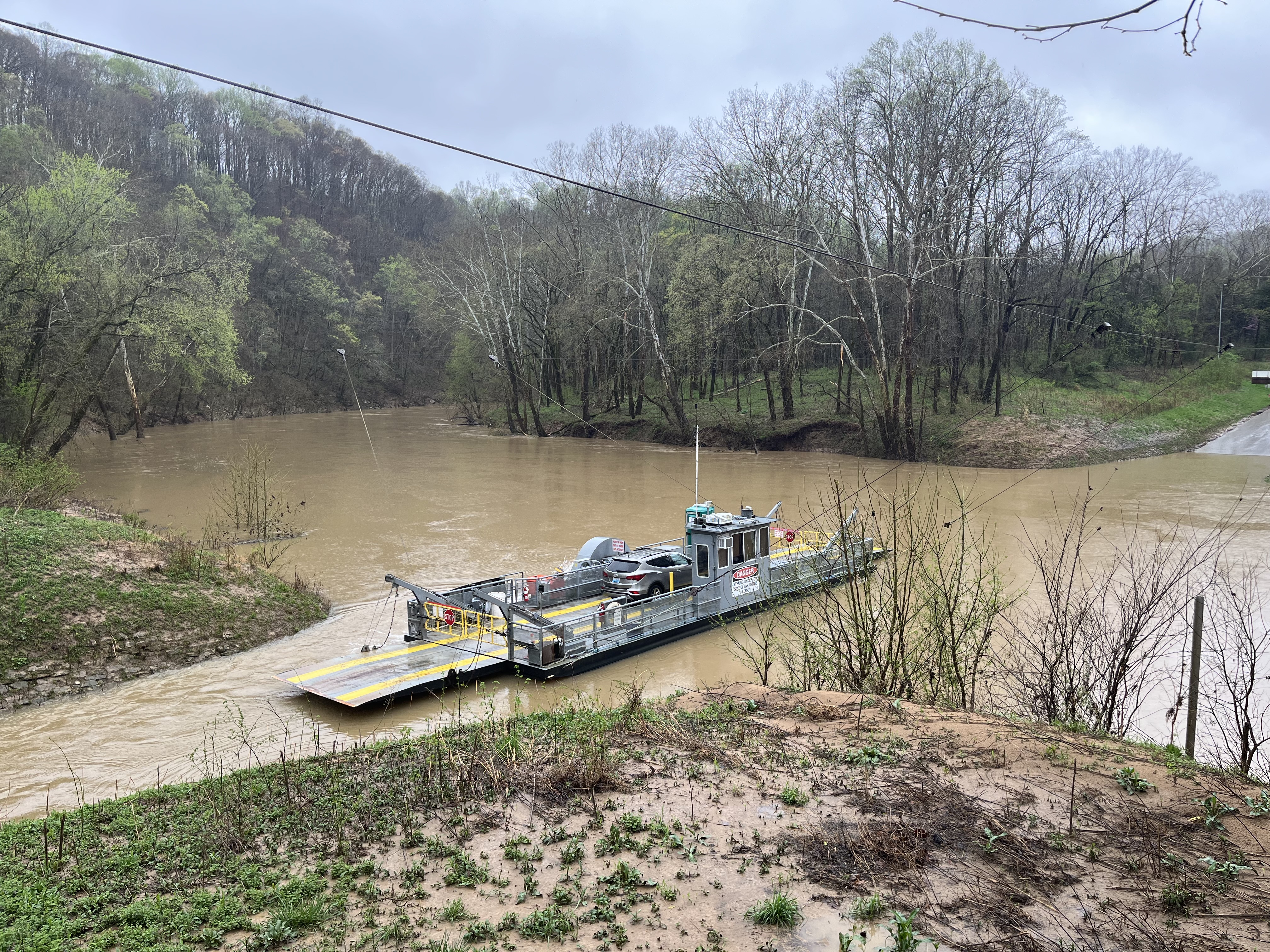 Green River Ferry in Mammoth Cave National Park A ferry boat carries a passenger vehicle across a swollen, muddy river.