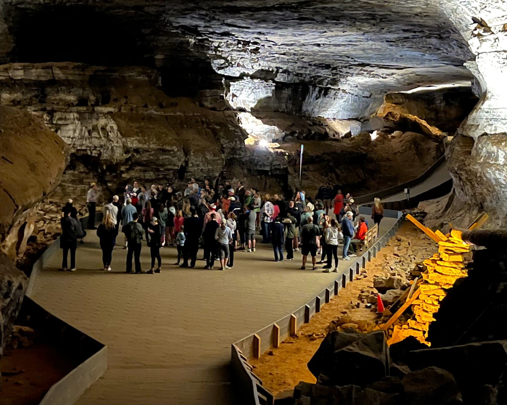 The Historic Tour stops at a cave room called "The Methodist Church" inside Mammoth Cave. A crowd of people stand inside a large rocky cave room.