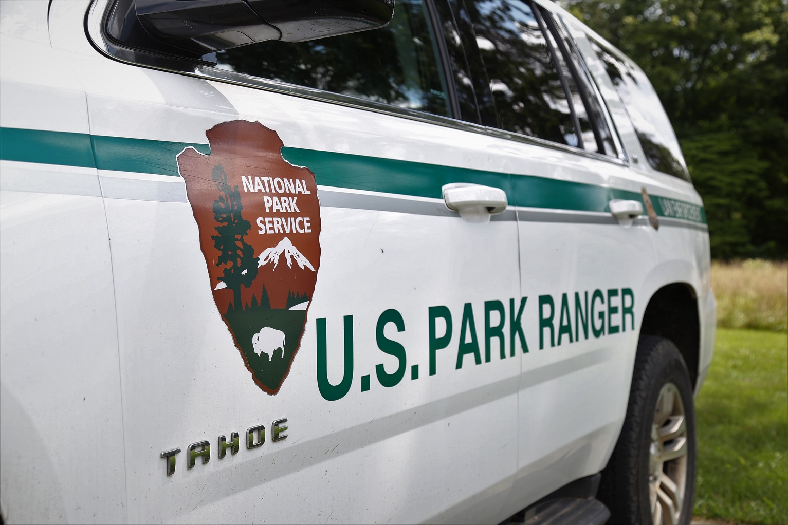 Mammoth Cave's law enforcement rangers provide safety and security for the park's visitors, employees, and its resources. The side of a white vehicle with the brown, green and white National Park Service Arrowhead Logo and the words "U.S. Park Ranger" written in green.
