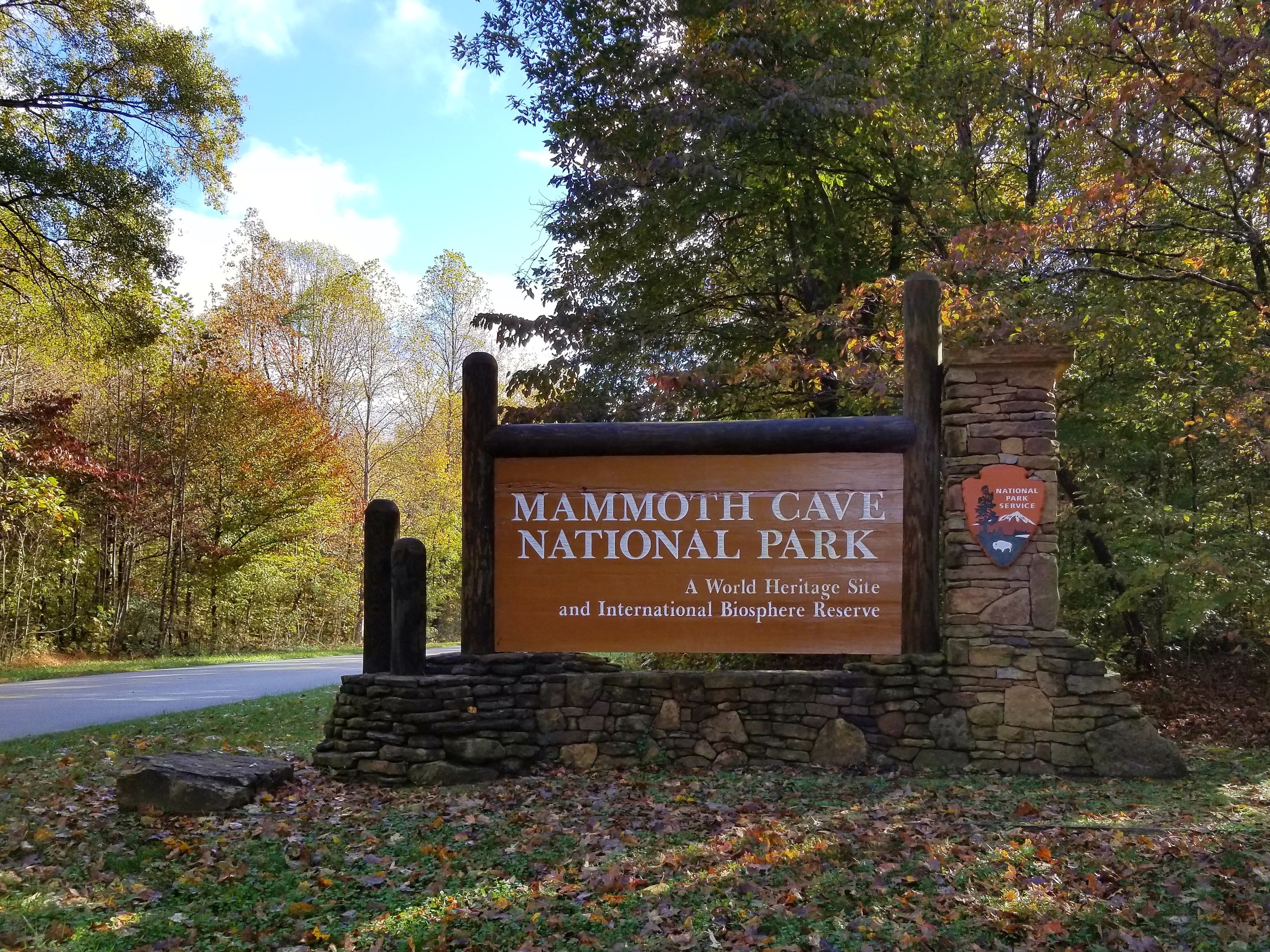 Mammoth Cave National Park entry sign at the entrance near Brownsville, KY. A large brown wooden entrance sign that reads, "Mammoth Cave National Park, a World Heritage Site and International Biosphere Reserve."