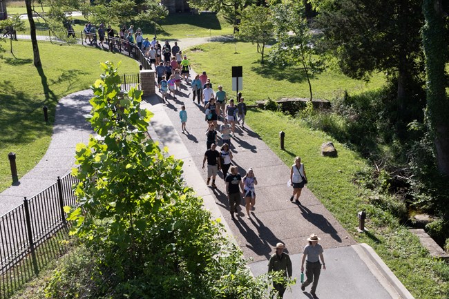 A group of people walk down a hill on a paved road.