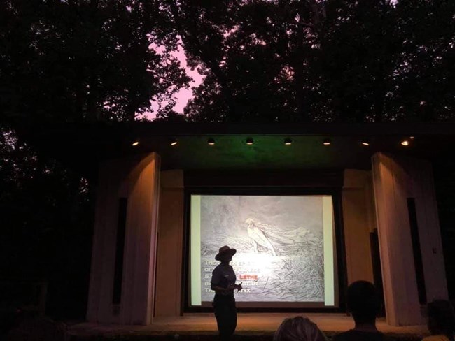 A ranger standing in front of a projector screen at an evening program