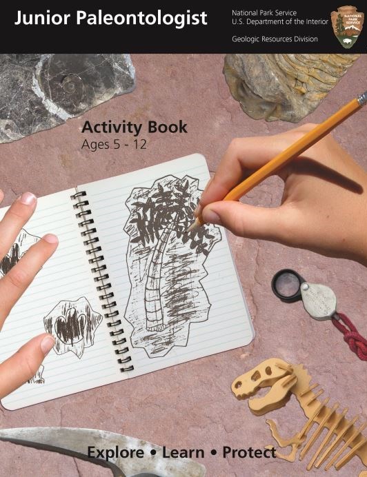 Junior Paleontologist, National Park Service, U.S. Department of the Interior, Geological Resources Division. Activity Book Ages 5-12. Image of hands drawing a picture of a palm tree in a notebook with dinosaur bones, rock fossils and magnifying glass.