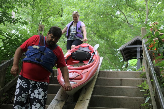 Two people moving a kayak down a ramp