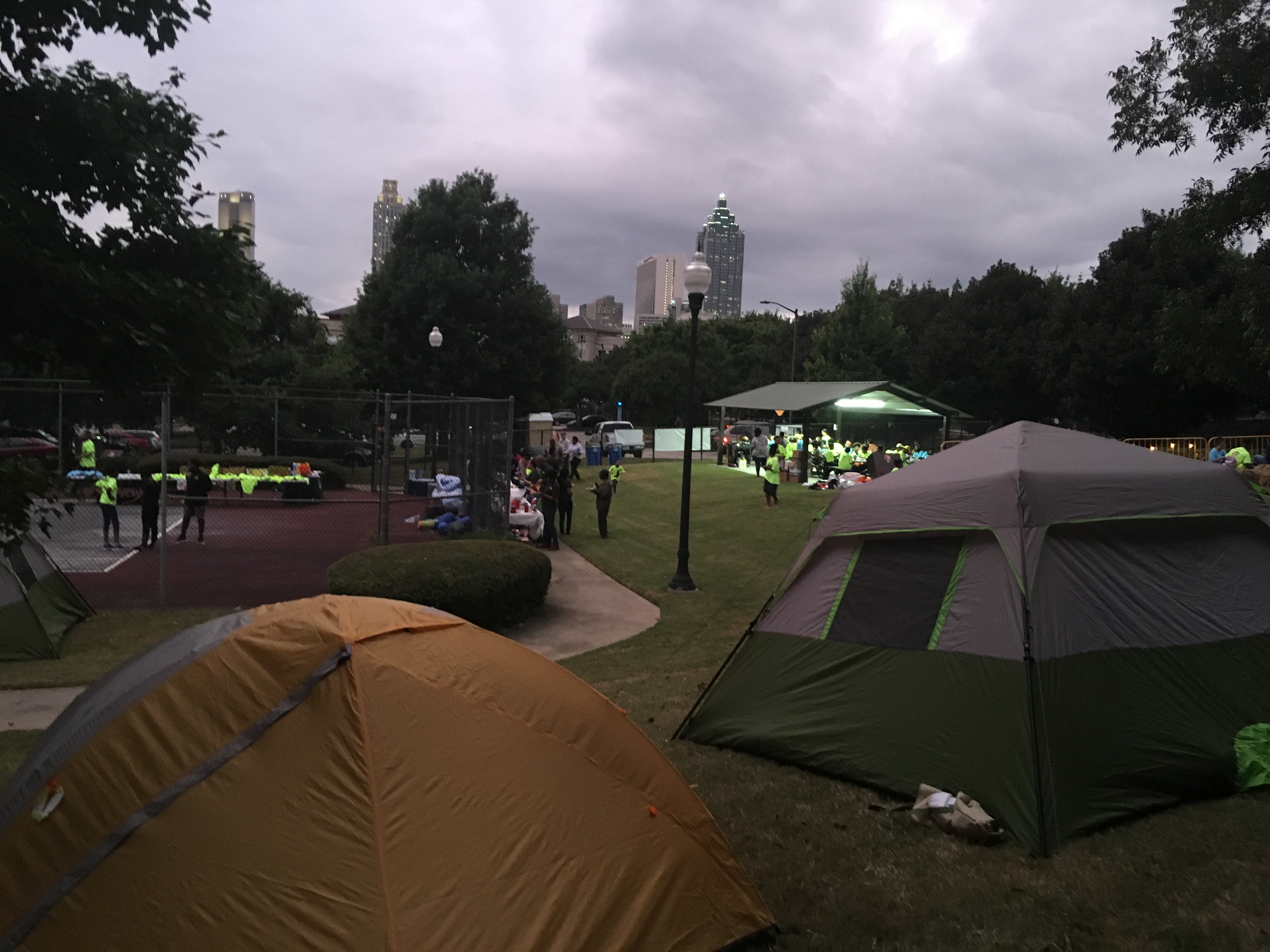 Camping tents and campers with downtown Atlanta skyline in background.