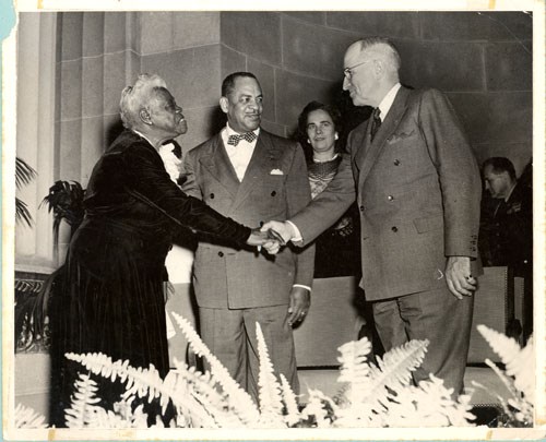 Mary McLeod Bethune shakes the hand of President Harry S. Truman as Congressman William L. Dawson observes, smiling