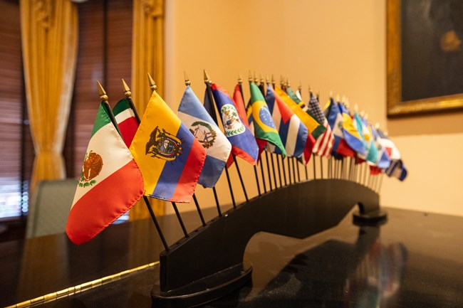 Miniature flags from the United Nations sit atop a piano.