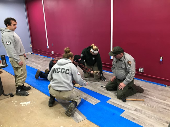 NCCC team members lay flooring with park maintenance staff.