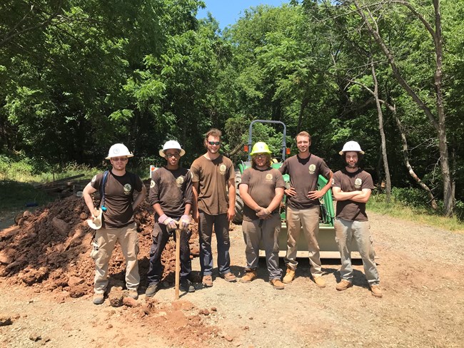 Members of an American Conservation Experience crew pose near a work site.