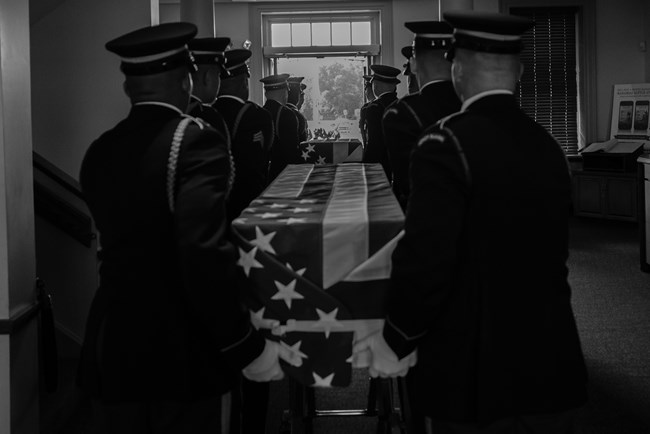 Army honor guard carries flag-draped boxes out of the Manassas Battlefield visitor center