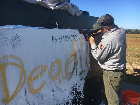 A National Park Service preservation expert works to clean white paint from the granite base of the Stonewall Jackson Monument at Manassas National Battlefield Park.