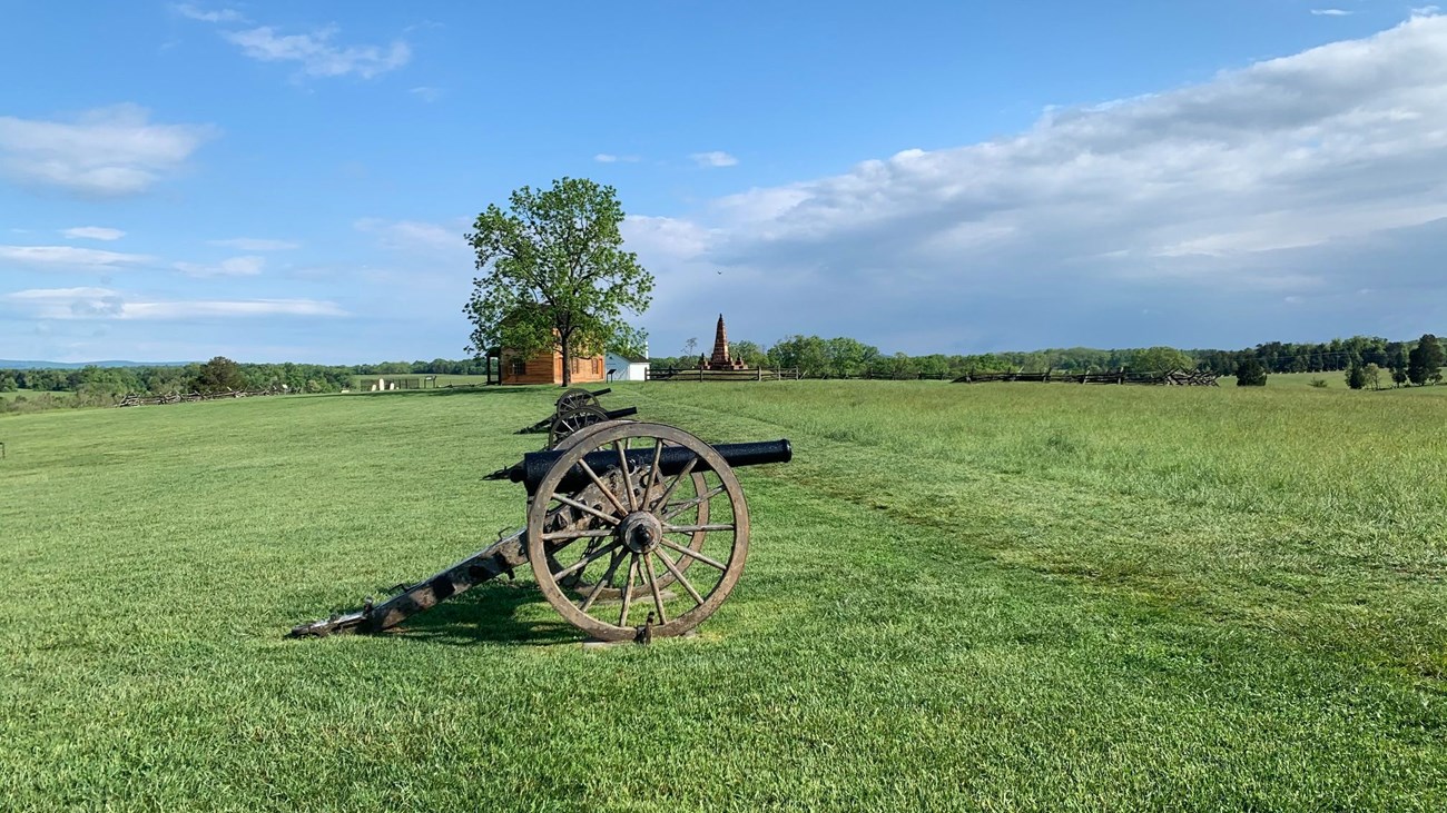 Row of artillery pieces on Henry Hill with the Henry House in the distance