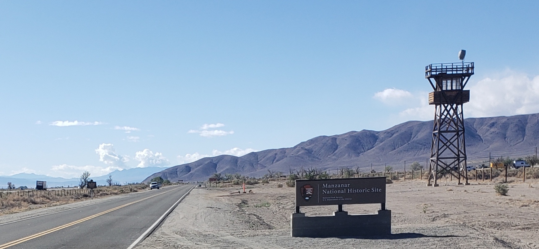 roadway on left, entrance sign in center, and guard tower on right