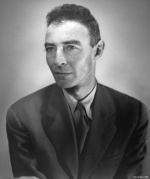 A black and white portrait photo of a man in a black suit jacket and tie.