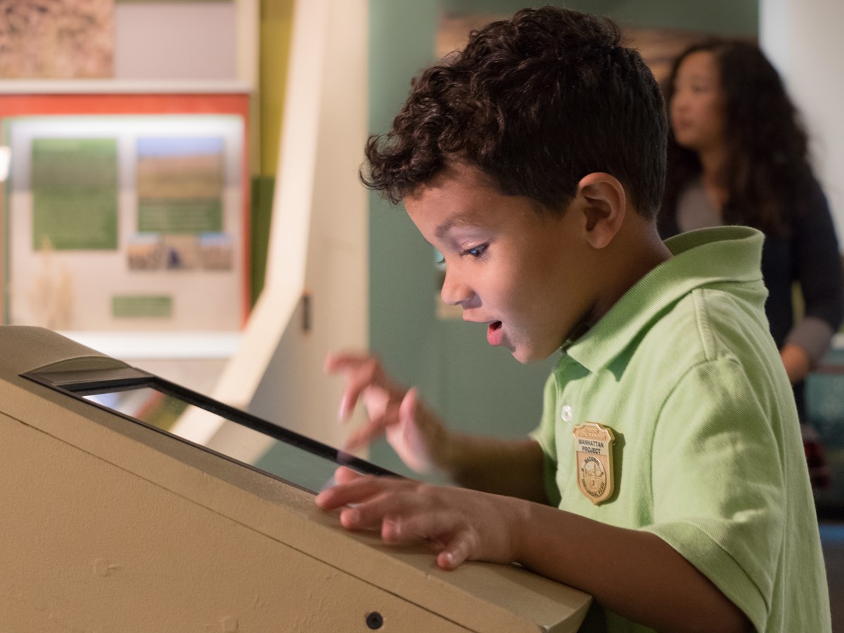A child wearing a green polo shirt interacts with an exhibit.