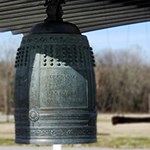 A large metal bell decorated in motifs symbolizing peace.