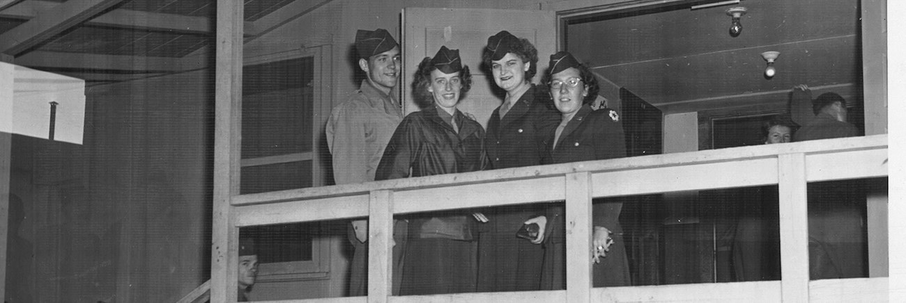 Black and white photo of four people in uniforms on a deck.
