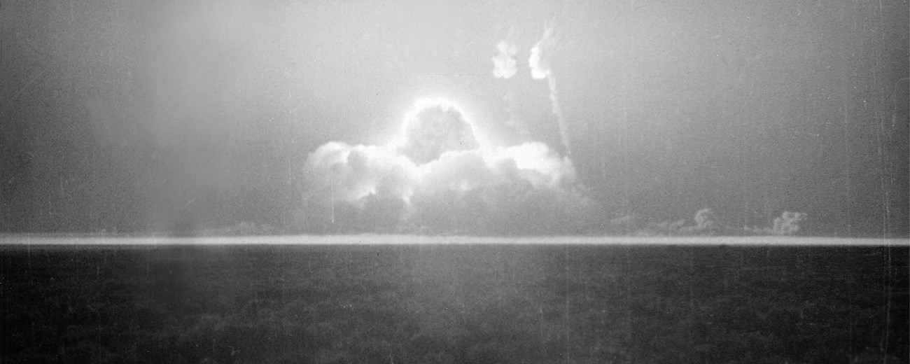 Black and white photo of an atomic explosion in a flat desert.