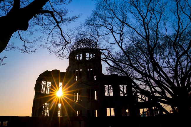 Color photo of a building in ruins and silhouetted.