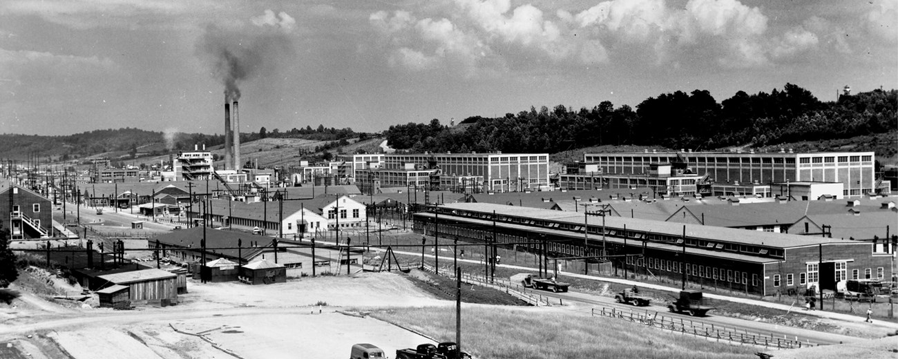 Black and white photo of a large industrial complex nestled in a narrow valley.