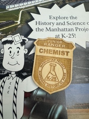 a wooden junior ranger badge on top of a junior ranger book.
