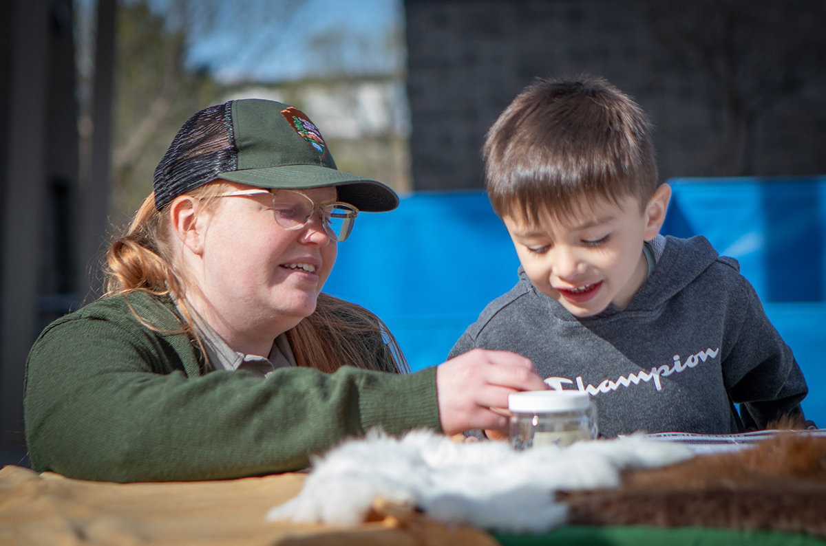 4_7_22_PopUpPlayday_Murphy lower res-22 Photo of woman showing a boy an item on table.