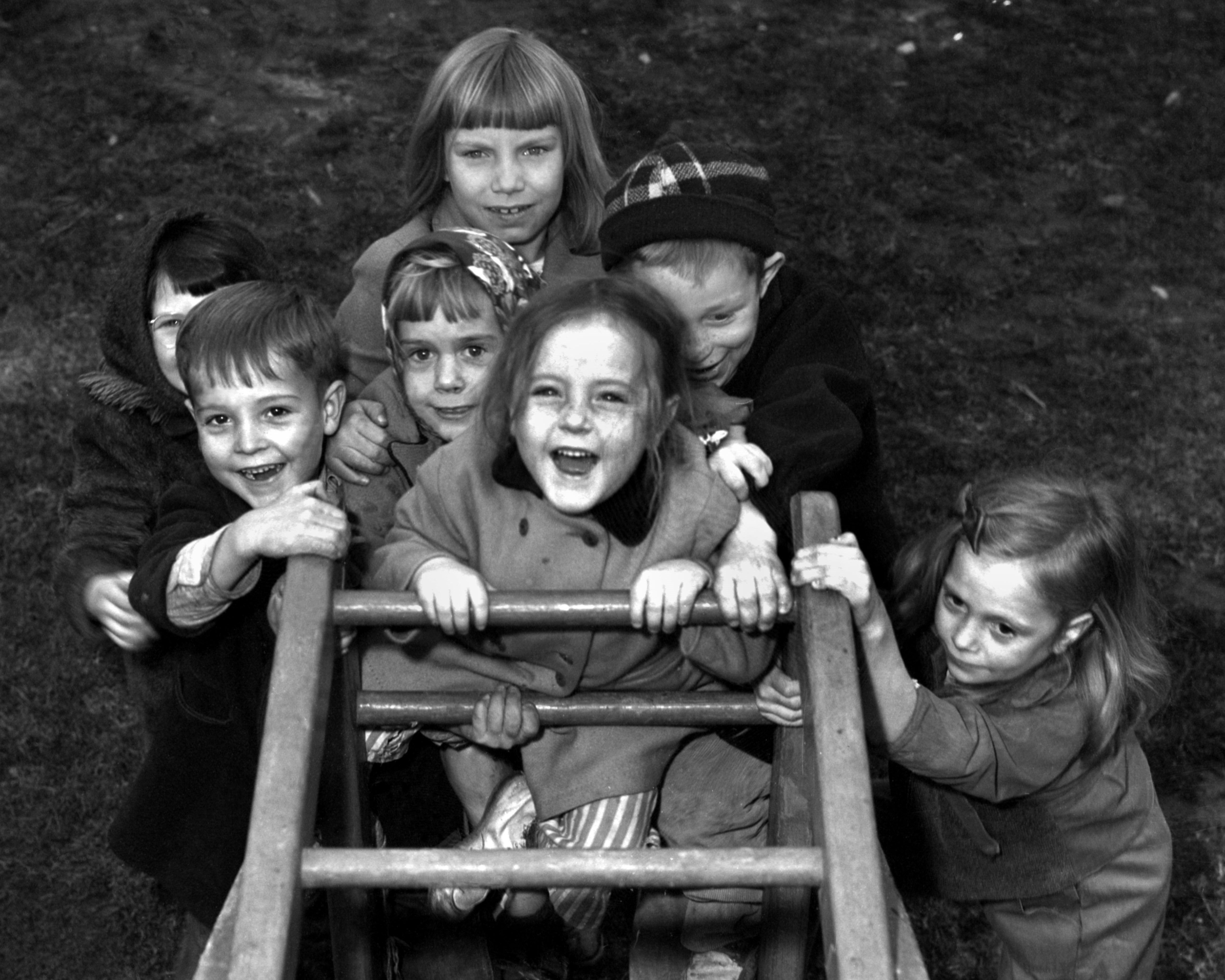 A gaggle of children climb up a play set, viewed from above