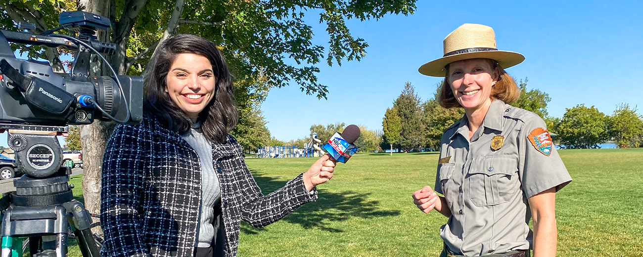 A woman with a microphone is interviewing a woman in a ranger uniform.