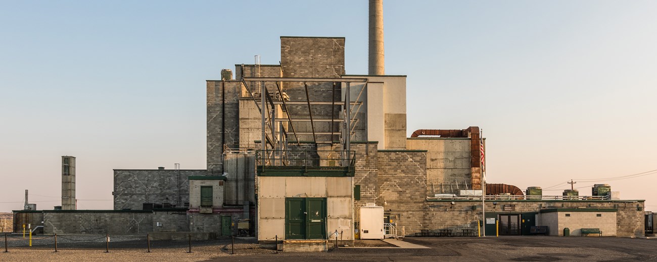 A large blocky reactor building photographed at sunset, with a large ventilation stack protruding from the upper right.